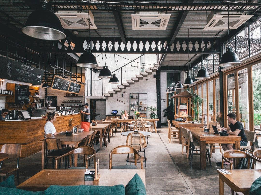 奧馬哈現代餐廳 - 美食藝術的巔峰 壁紙 — 現代工業風咖啡館，有裸露橫樑、木桌、吊燈，顧客在工作或放鬆。