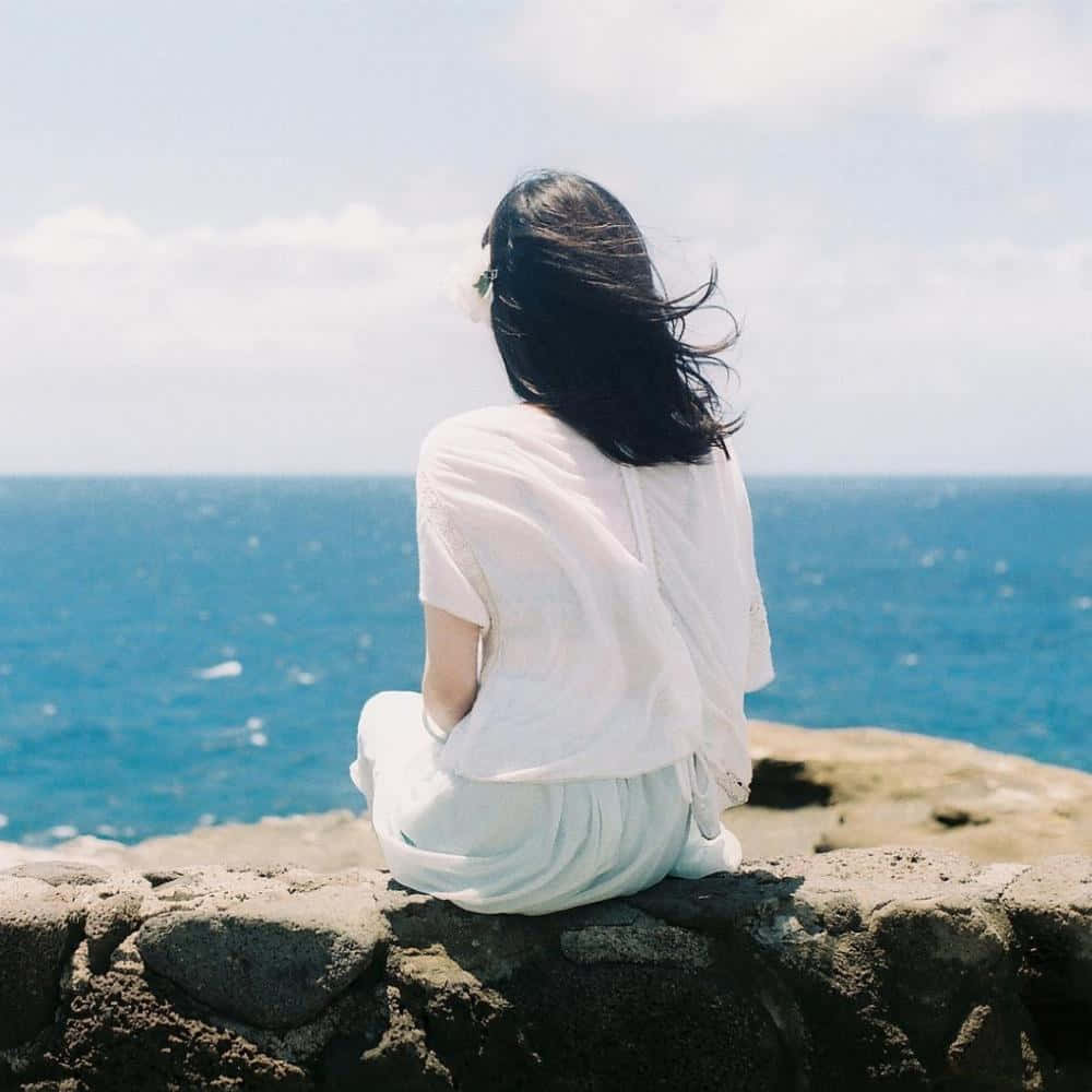女人坐在岩石上俯瞰海洋 壁紙