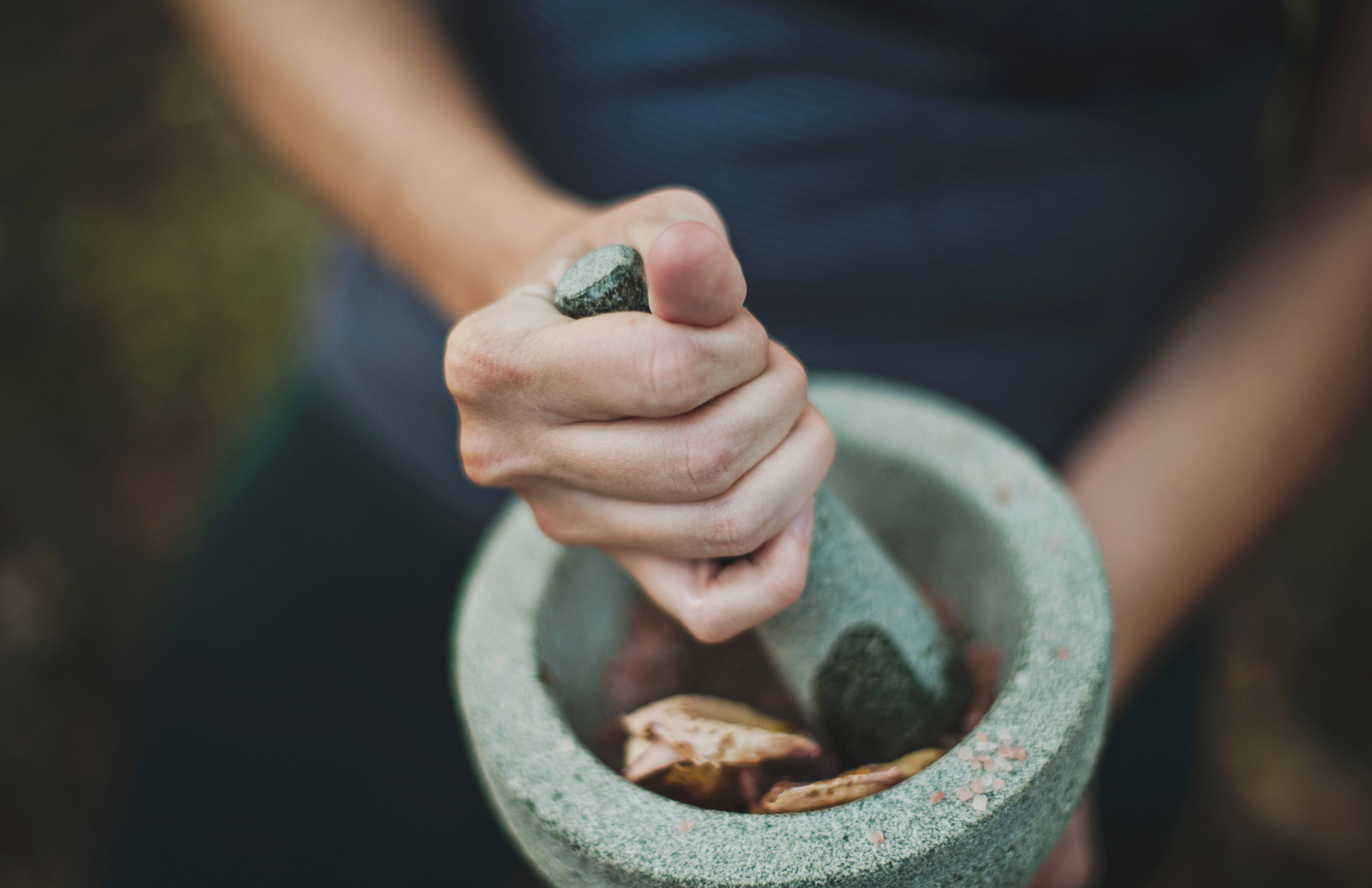 女子於森林中練習瑜伽 壁紙 — 手部特寫，在石臼中研磨香料，帶有大地色調和柔和自然光。