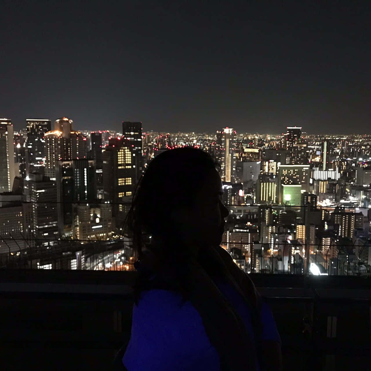剪影中的人俯瞰夜晚充滿活力的城市。