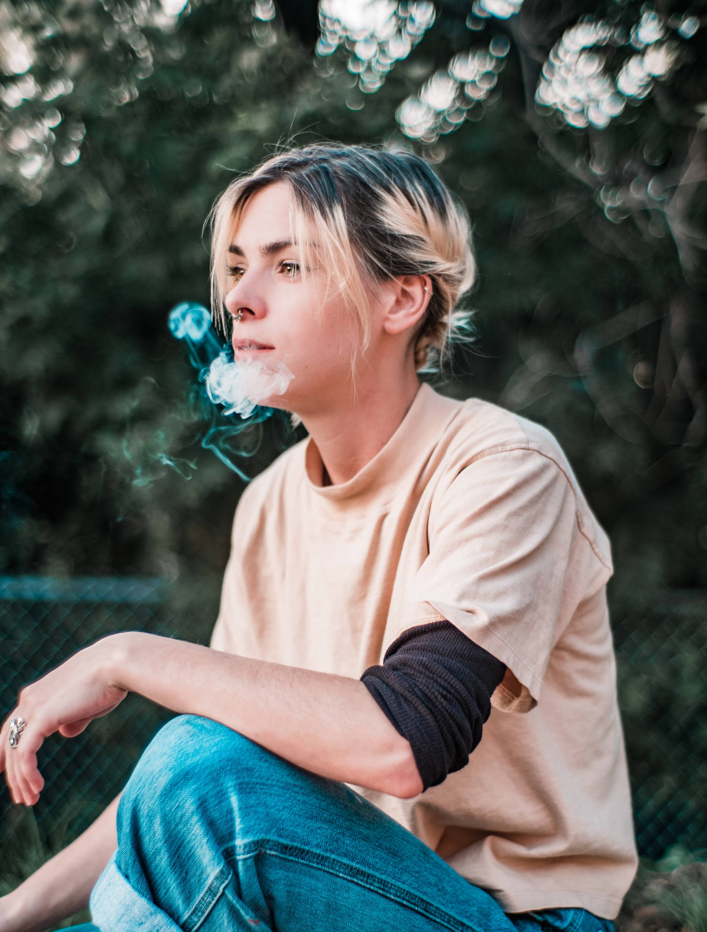 年輕女性坐在戶外綠意中呼出蒸氣。