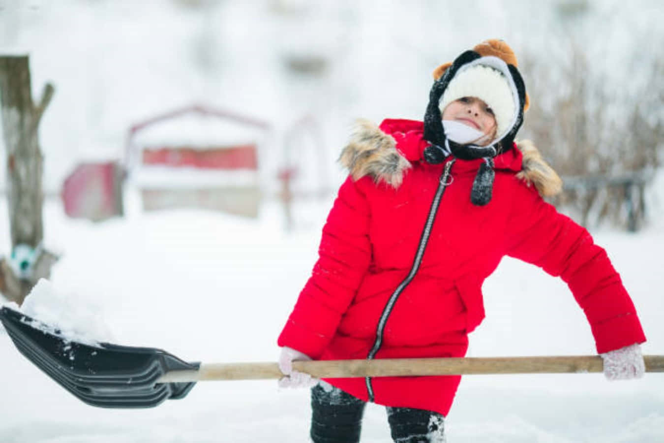 孩子穿著冬季外套在戶外鏟雪