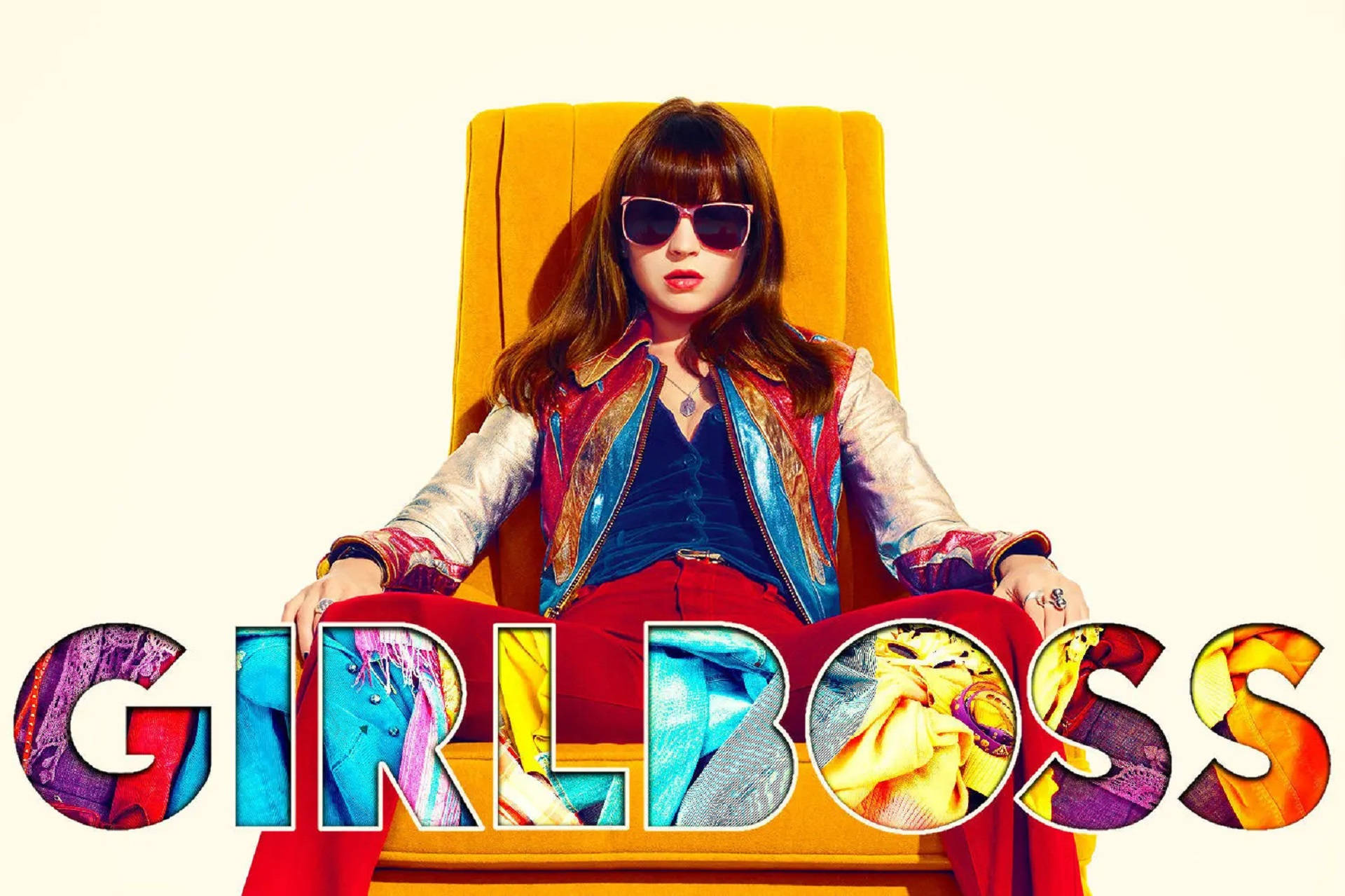 一位戴著太陽眼鏡和色彩繽紛夾克的女性，坐在黃色椅子上，下方有「GIRLBOSS」文字。