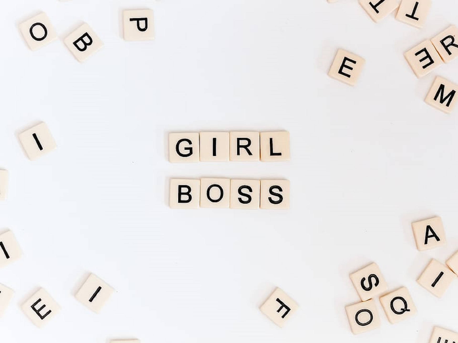 木製拼塊在白色背景上拼出 girl boss，周圍散落字母。
