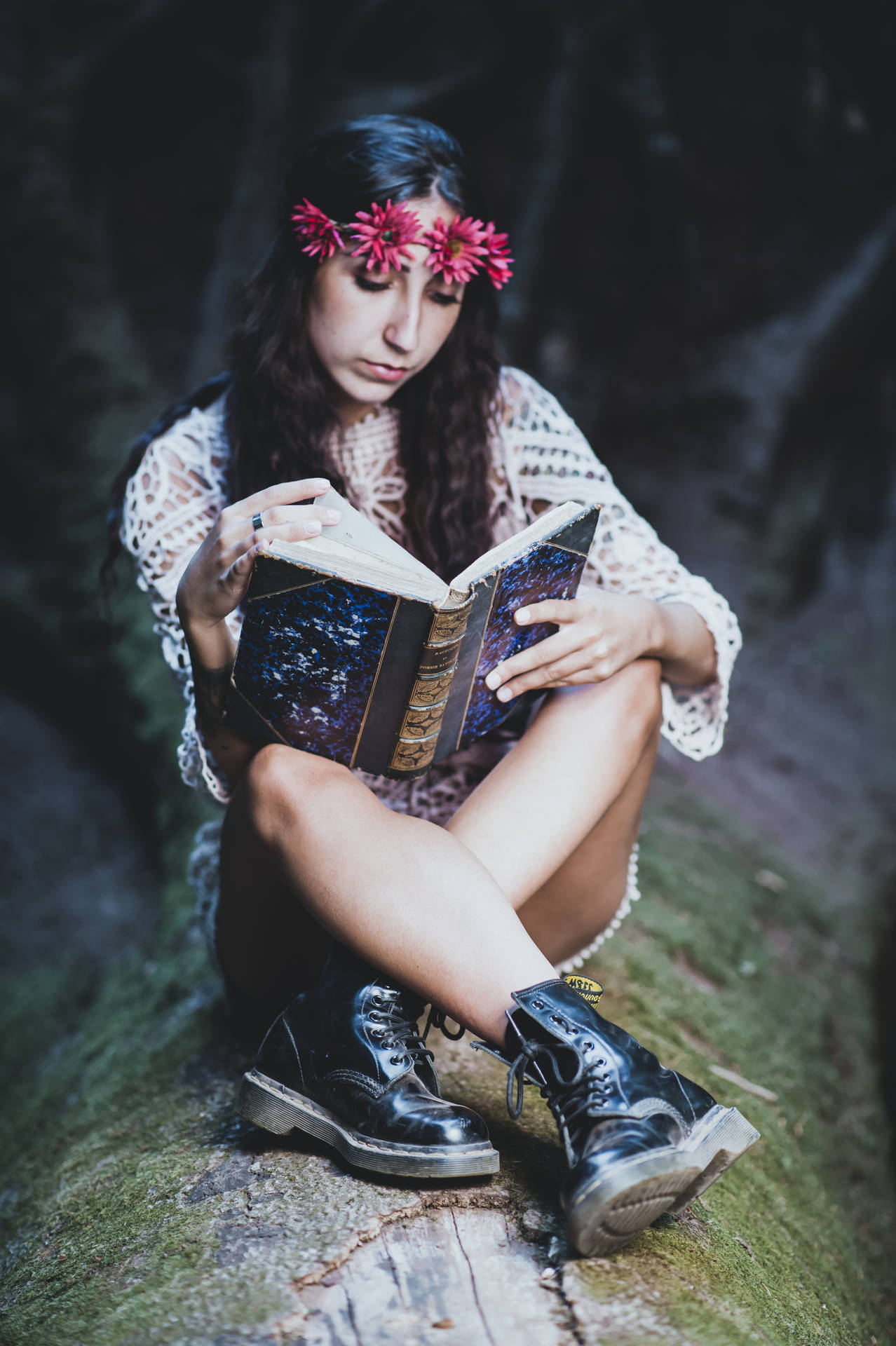 戴花冠的女子在森林的苔蘚木頭上讀書