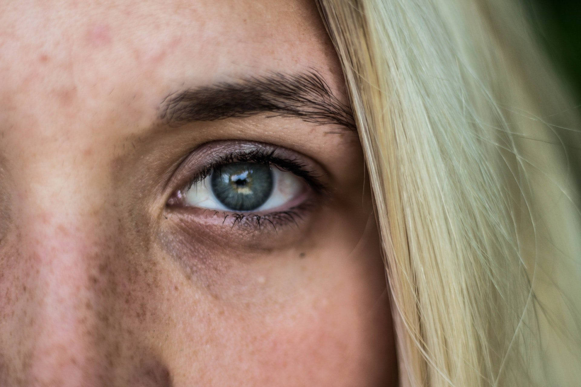 Eye 桌布 壁紙 — 女性引人注目的藍色眼睛特寫，金色頭髮勾勒側面，捕捉原始的人類細節。