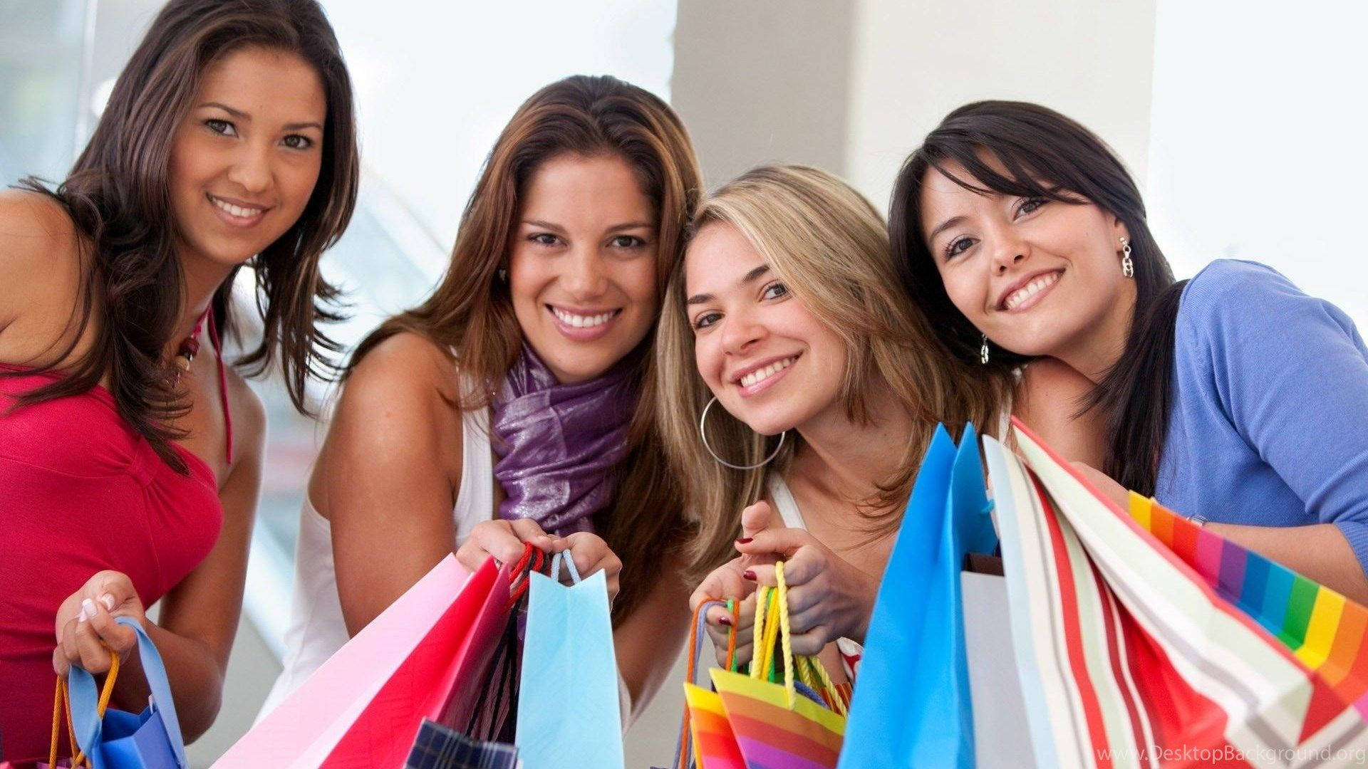 四位快樂的女性在室內手持購物袋。