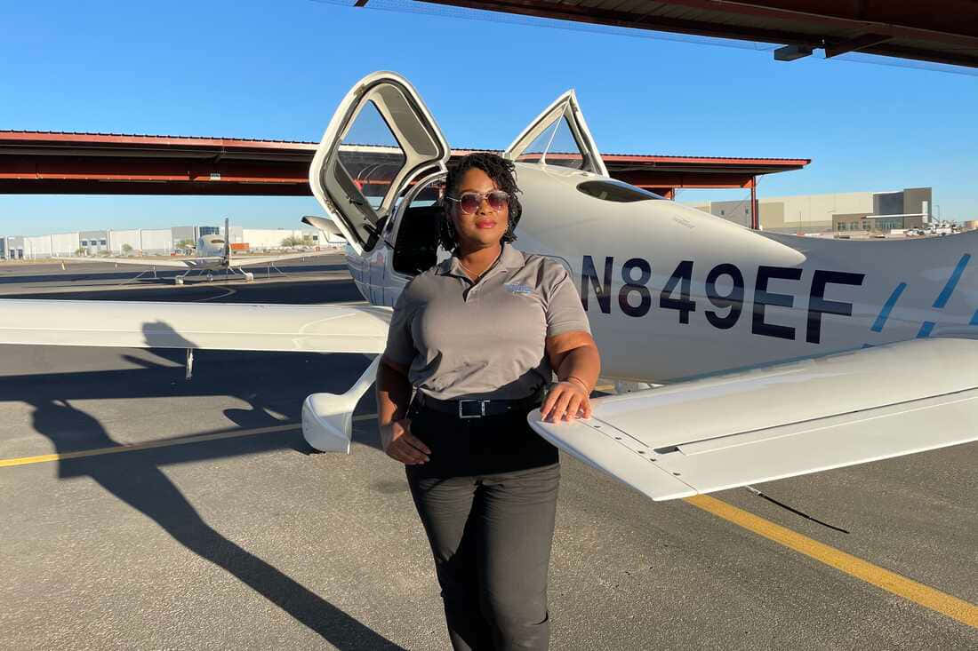 戴太陽眼鏡的女性站在停機坪上的白色小型飛機旁
