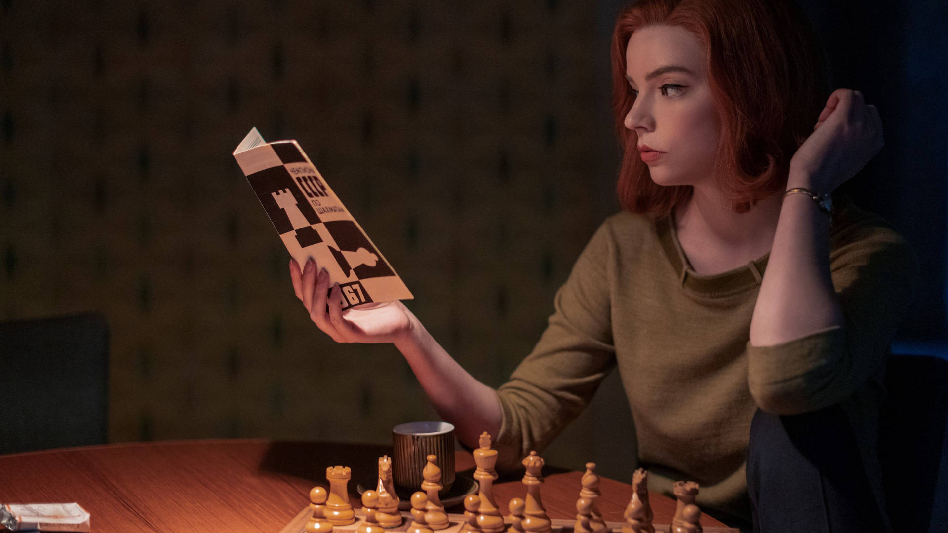 女士在昏暗房間裡閱讀棋盤上的國際象棋書