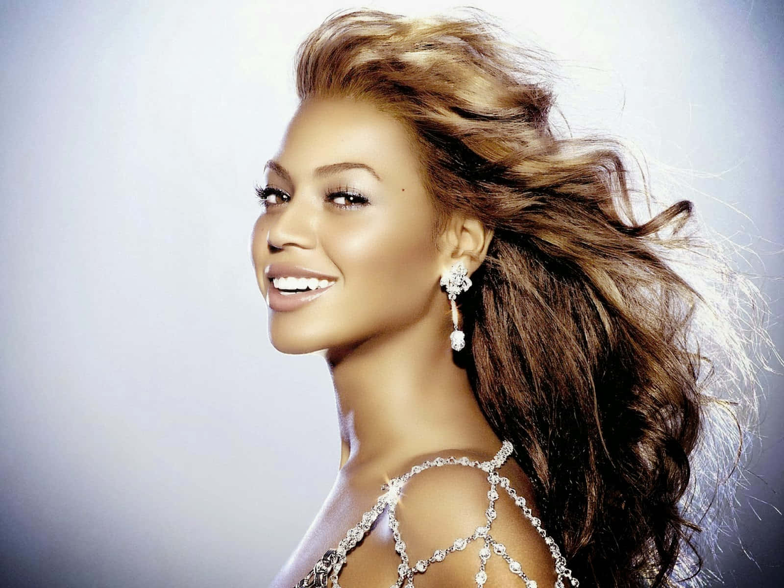 「女王碧昂絲」 壁紙 — Beyoncé 在柔和的漸變背景前，秀髮飄逸，閃爍的鑽石耳環，燦爛微笑。