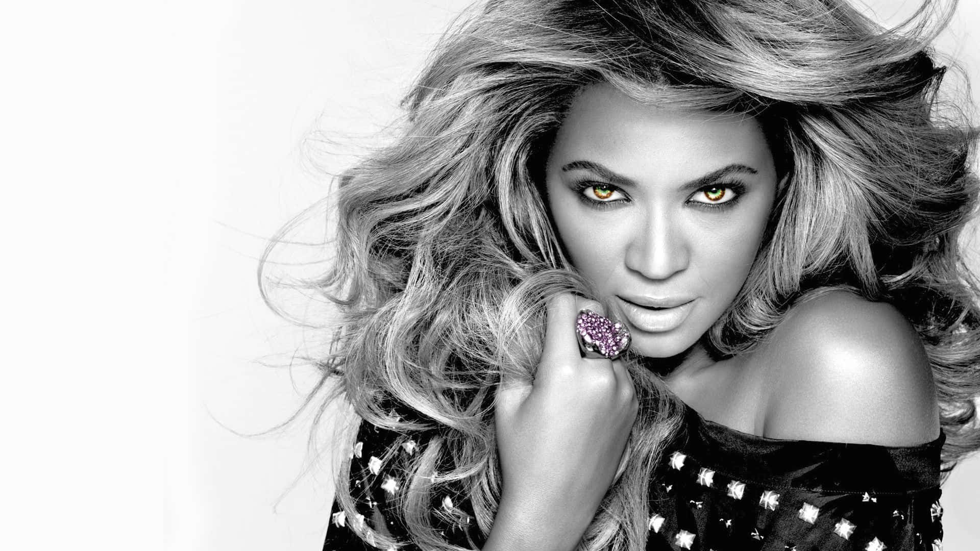 女王碧昂絲登場！ 壁紙 — Beyoncé 以金色眼睛和飄逸頭髮在高對比黑白肖像中凝視。
