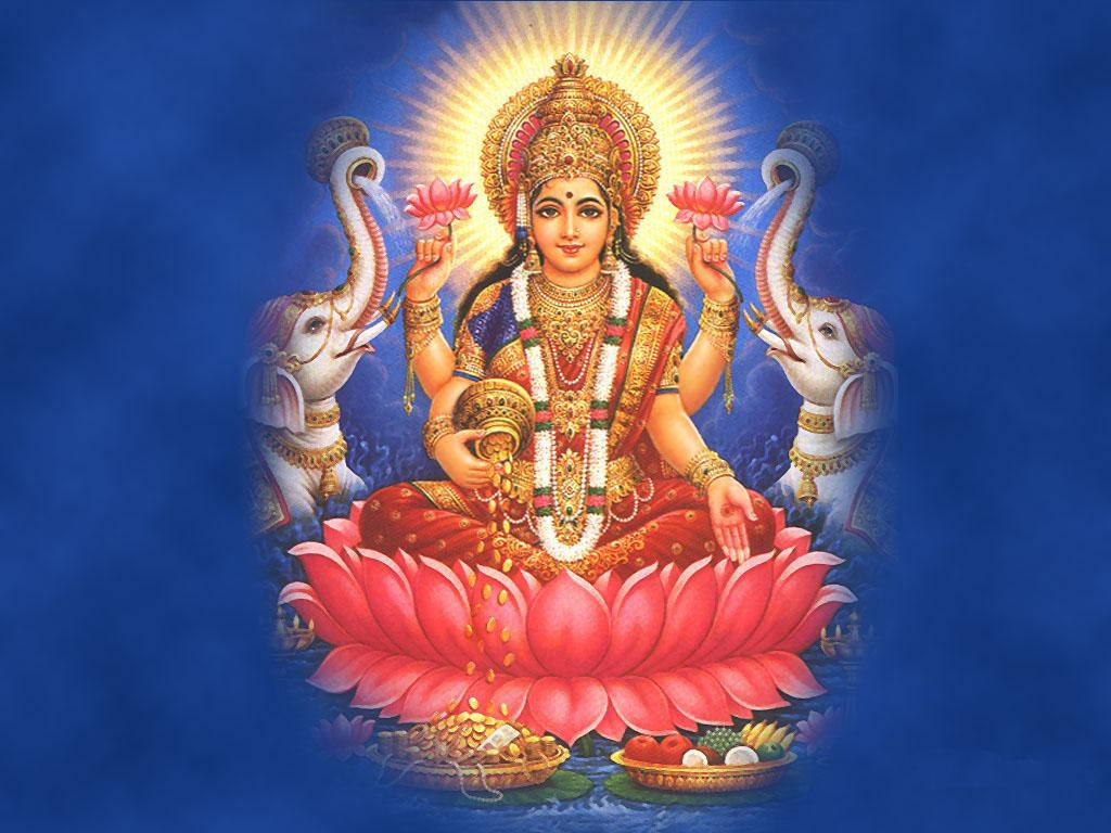 Lakshmi 桌布 壁紙 — 女神拉克什米坐在粉紅色蓮花上，光芒四射，帶有金色光環，手持蓮花，兩側有大象，背景為深藍色。