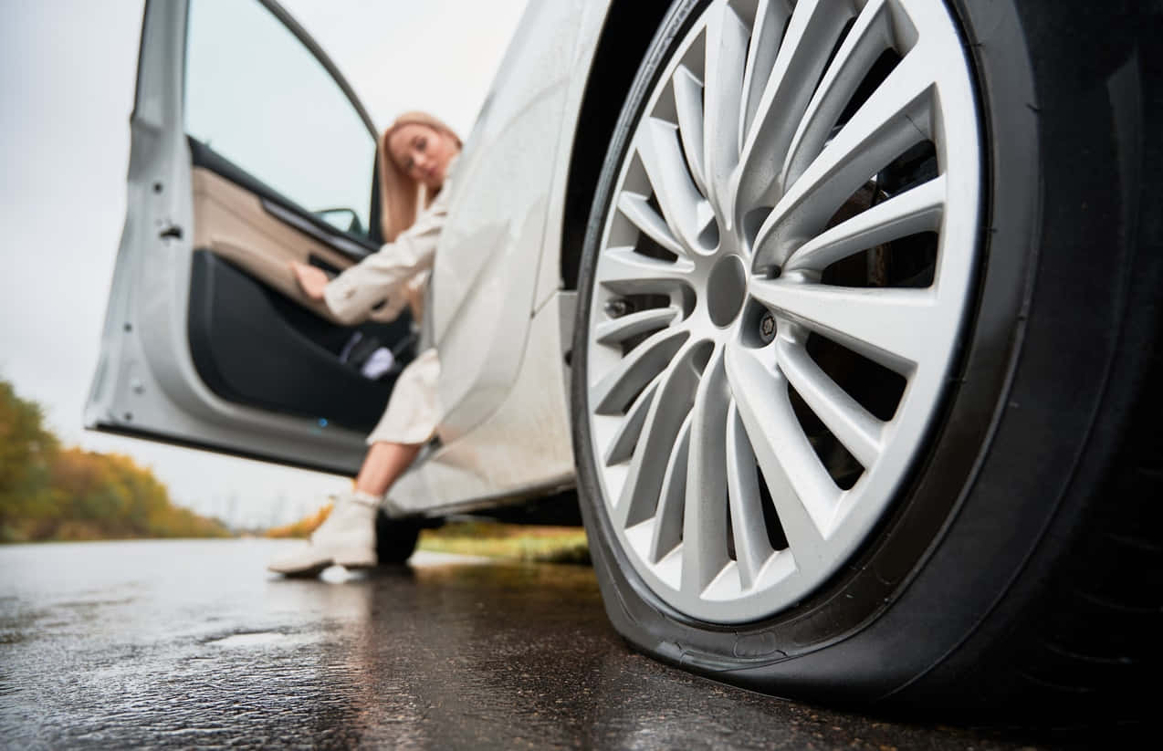 女子在潮濕的秋日道路上從白色汽車中走出
