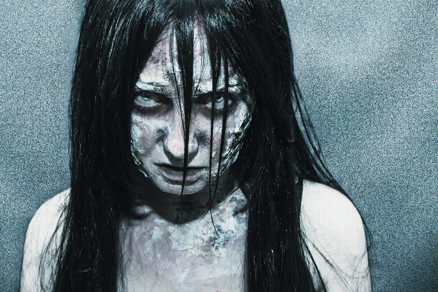 女鬼嚇人圖 壁紙 — 一個令人難忘的肖像，一個皮膚蒼白、腐爛、黑髮的女人，背景是粗糙的灰色牆壁。