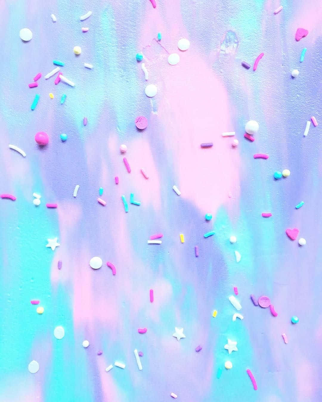 柔和藍色和粉紅色油漆背景，帶有色彩繽紛的糖粒和星星。