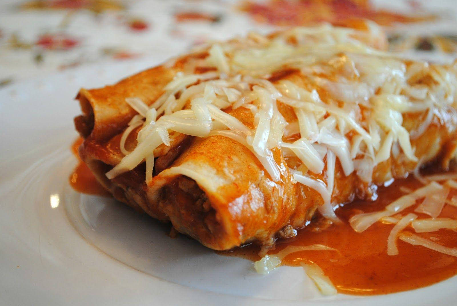 奶酪 enchiladas 特寫 壁紙 — 金黃色的玉米卷餅浸在濃郁的紅醬和融化的芝士中，誘人地放在白色碟子上。