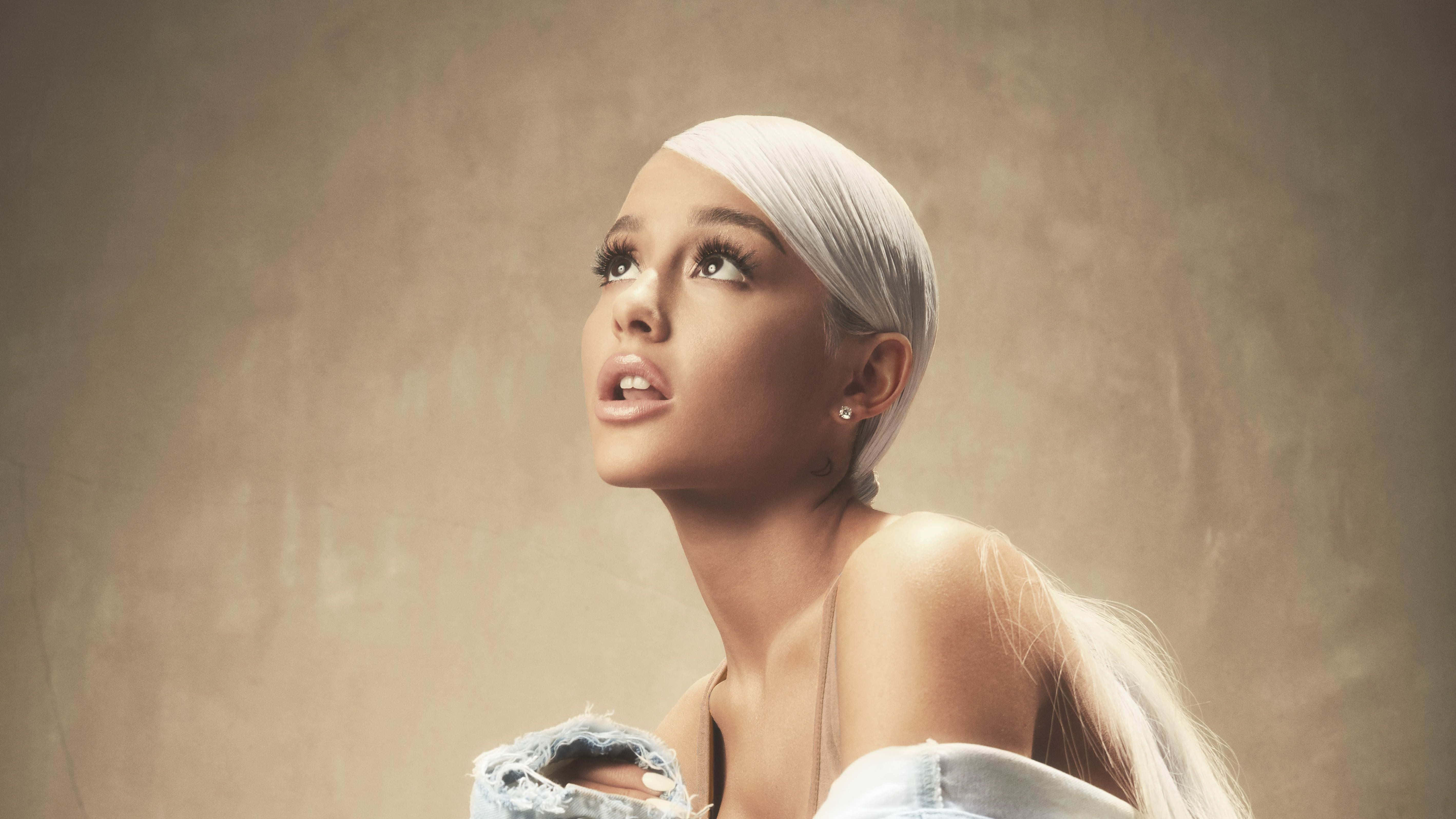 她將長久駐留——愛莉安娜·格蘭德 壁紙 — Ariana Grande 擁有鉑金色頭髮，在紋理米色背景下穿著破洞牛仔褲向上凝視。