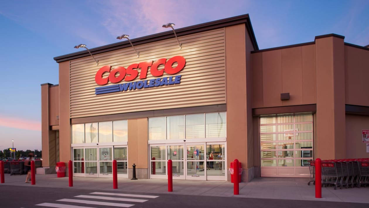 黃昏時分的Costco Wholesale商店外部，帶有紅色護柱和購物車。