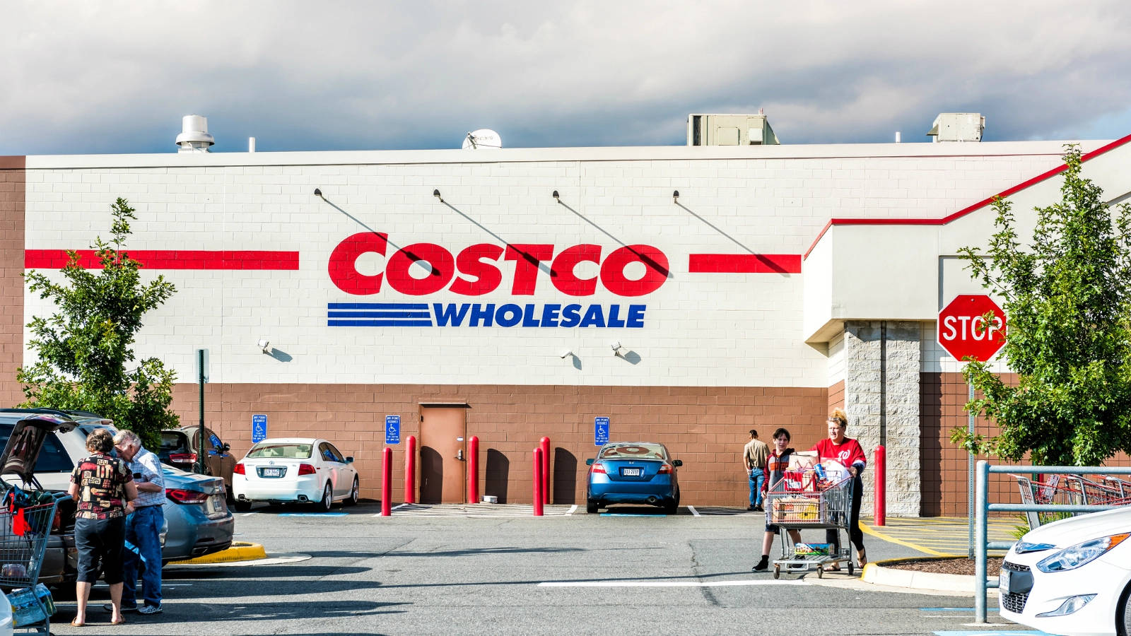 購物者推著購物車在多雲的日子裡在 Costco Wholesale 商店外。