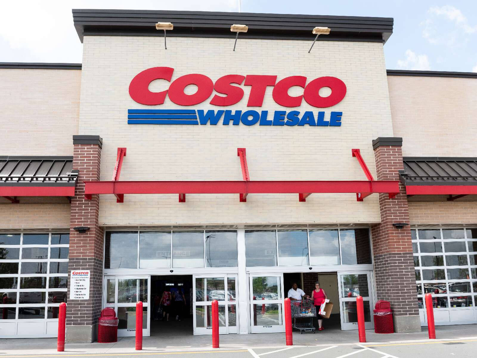 Costco Wholesale 商店入口，有購物者進入和紅色護柱。