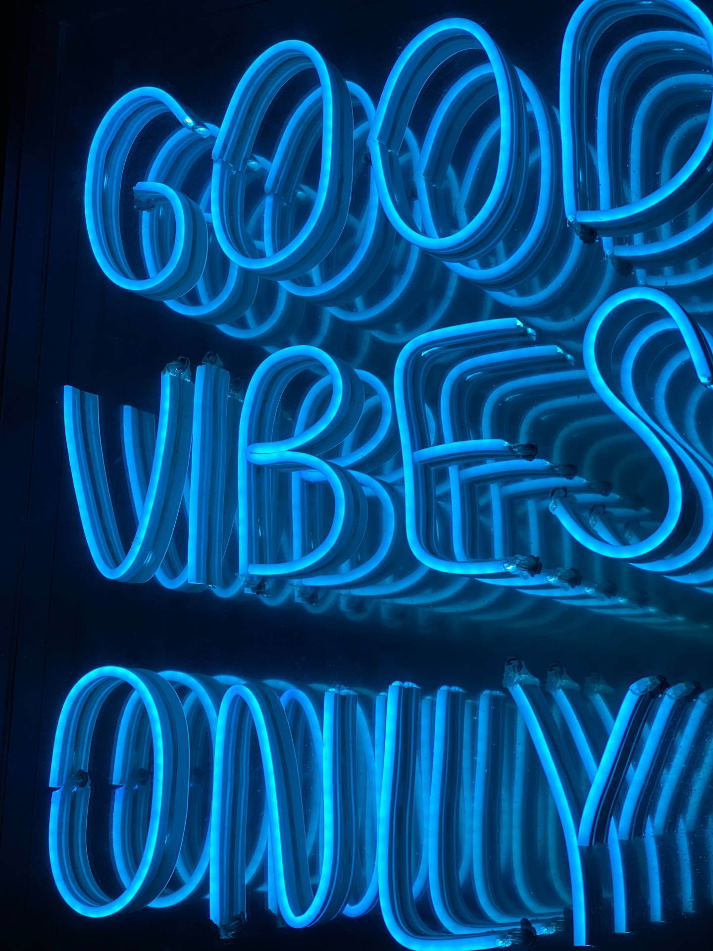 在黑暗房間中，藍色霓虹燈牌顯示「good vibes only」。