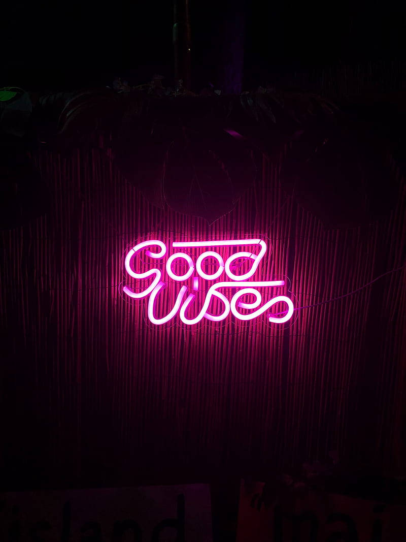 粉紅色霓虹燈牌寫著 Good Vibes，以深色竹簾為背景。