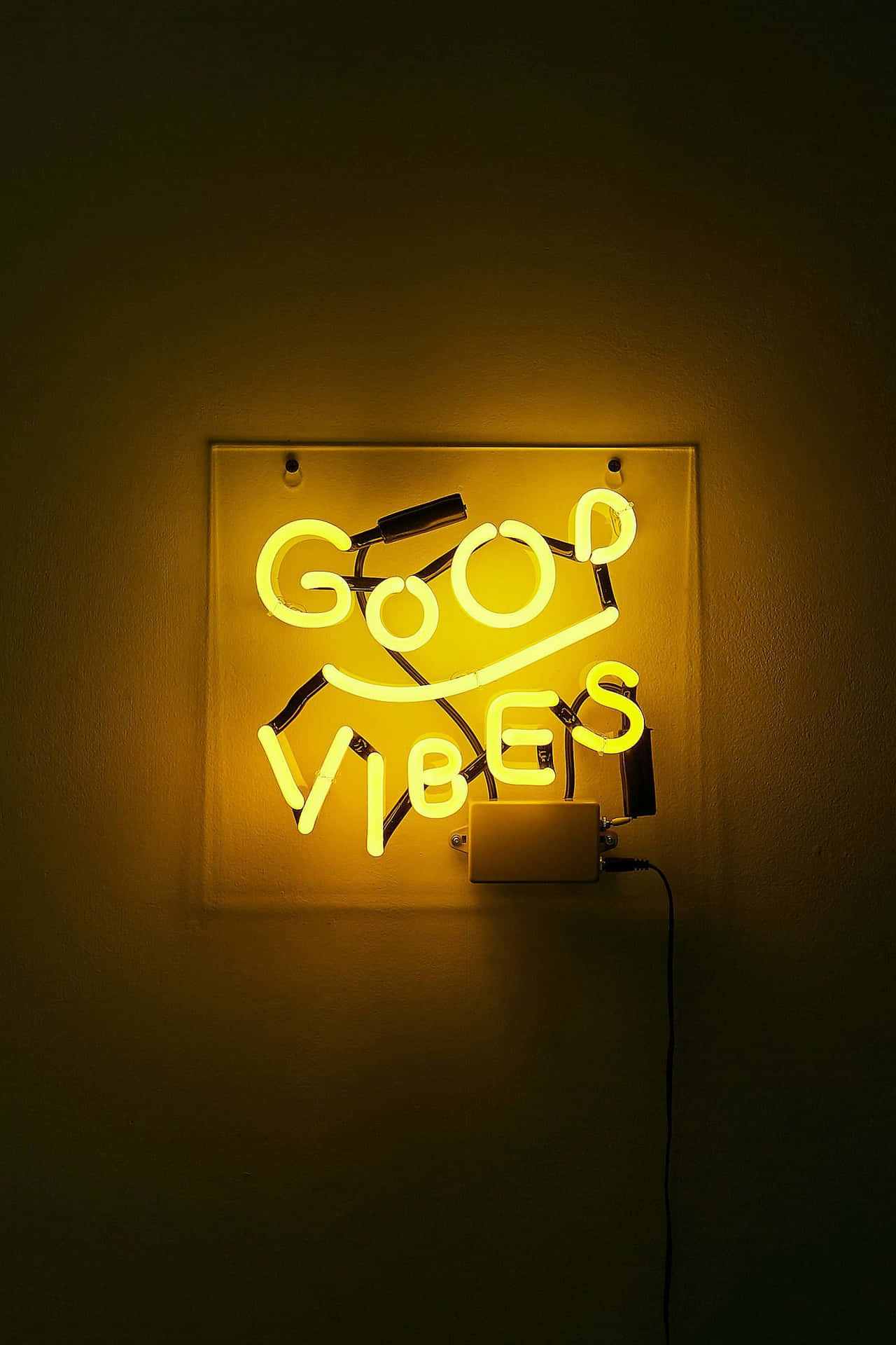帶有笑臉的黃色霓虹燈牌，在黑暗的牆壁上顯示good vibes。
