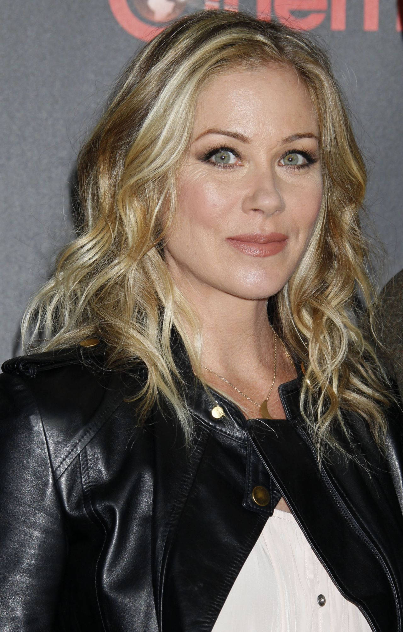 好萊塢出身女演員Christina Applegate 壁紙 — 一位擁有波浪金髮和綠色眼睛的女性在紅地毯活動中穿著黑色皮夾克。
