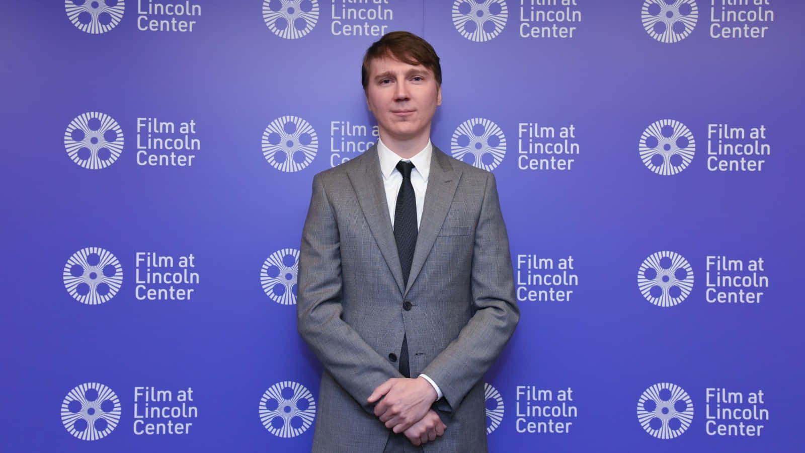 身穿灰色西裝的男子在Film at Lincoln Center活動中擺姿勢。