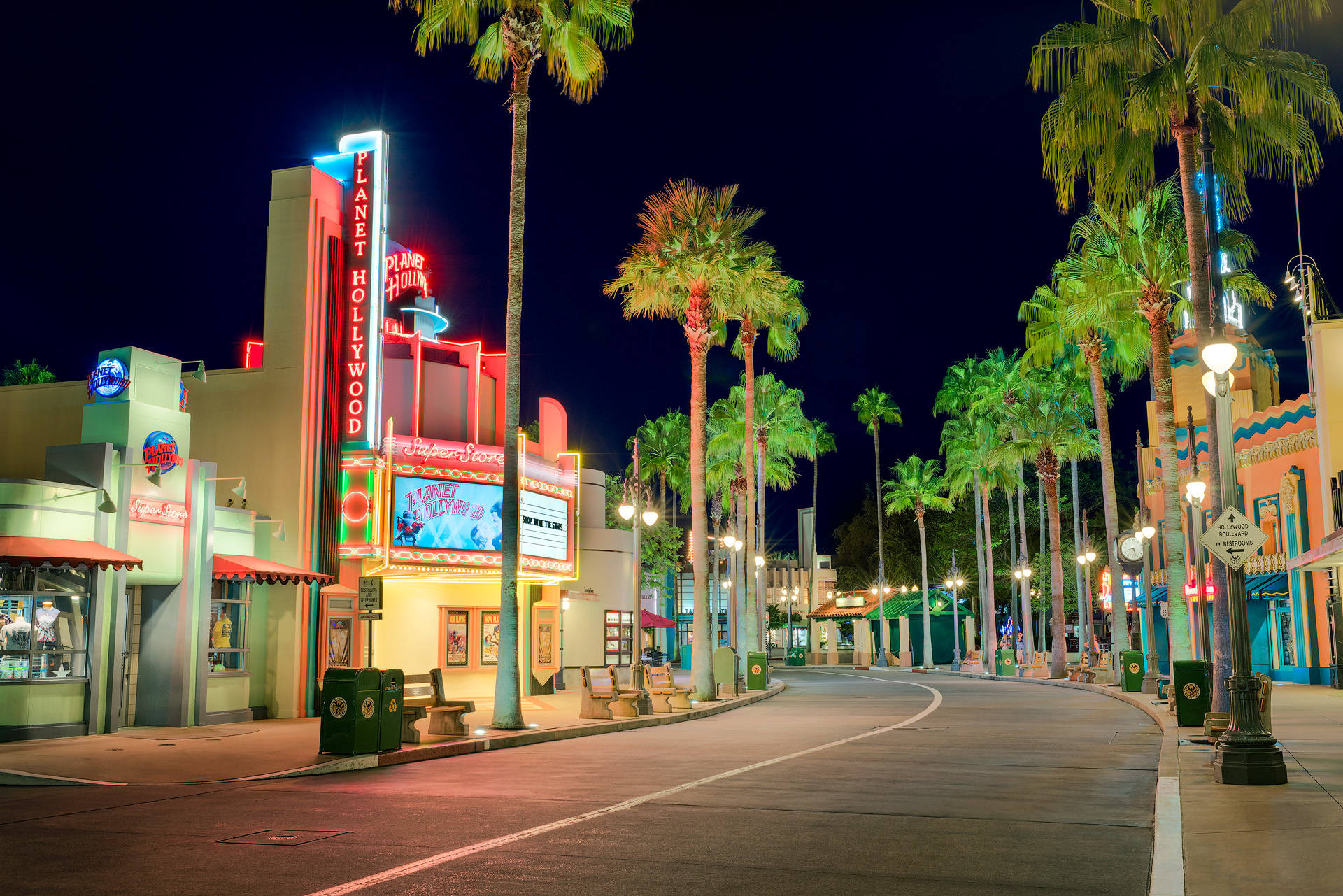 夜間街道，有棕櫚樹和 Planet Hollywood 閃爍的霓虹燈招牌。