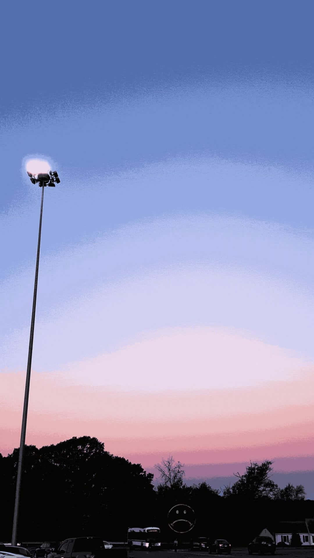 高燈柱在停車場上方的粉紅和藍色暮色天空下形成剪影。