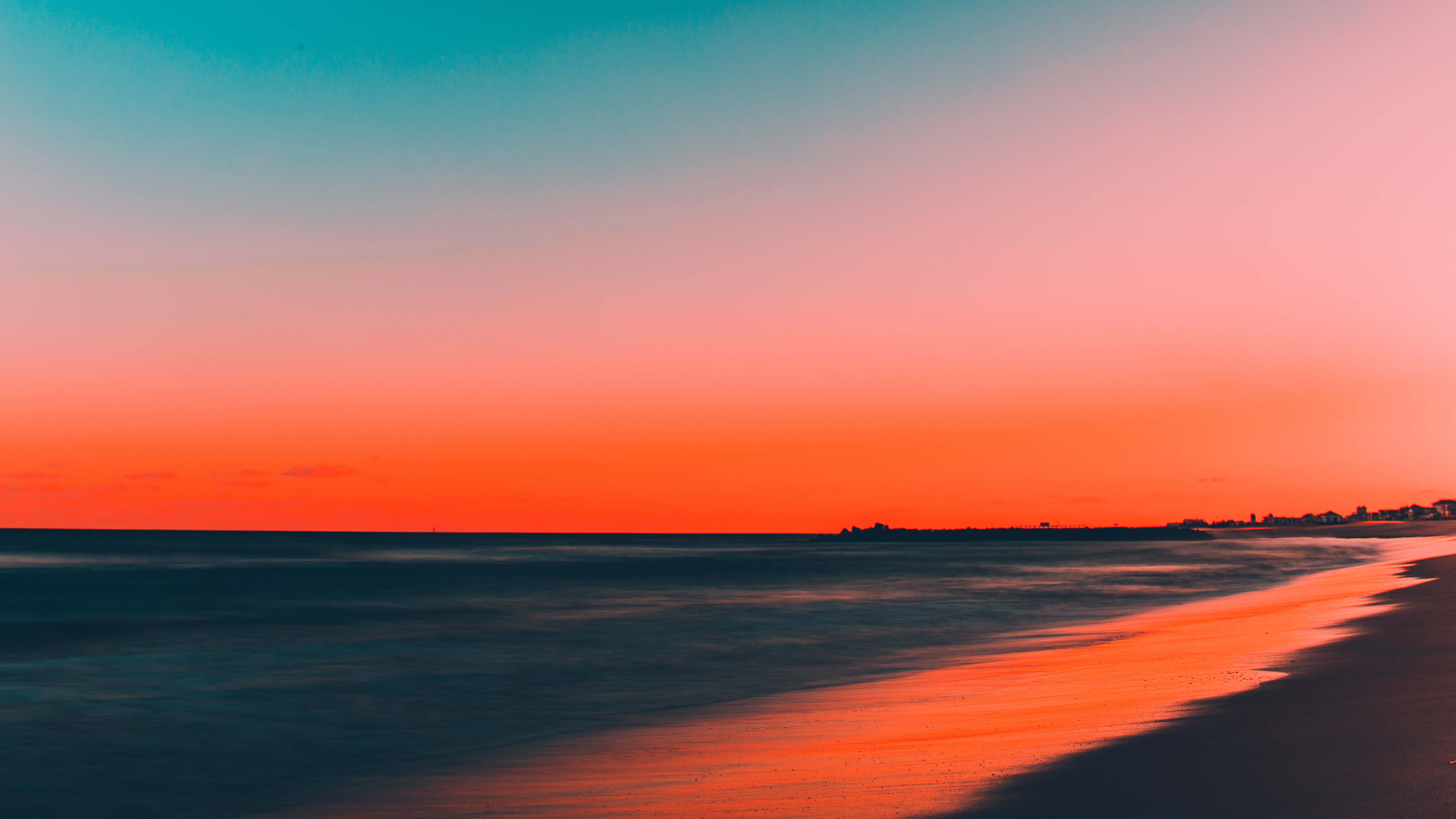 如畫的海灘天空 壁紙 — 日落時分的寧靜海灘，火紅色的天空映照在濕沙和平靜的海浪上。
