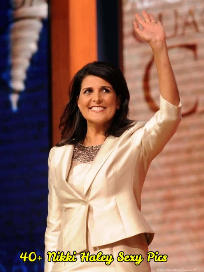妮基·海莉熱情向群眾揮手致意 壁紙 — Nikki Haley 身穿米色西裝外套，在磚牆和藍色背景下熱情揮手。