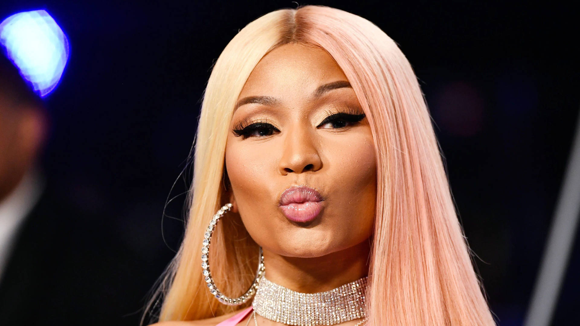 Nicki Minaj 在舞台燈光下嘟起嘴唇，戴著鑽石首飾。