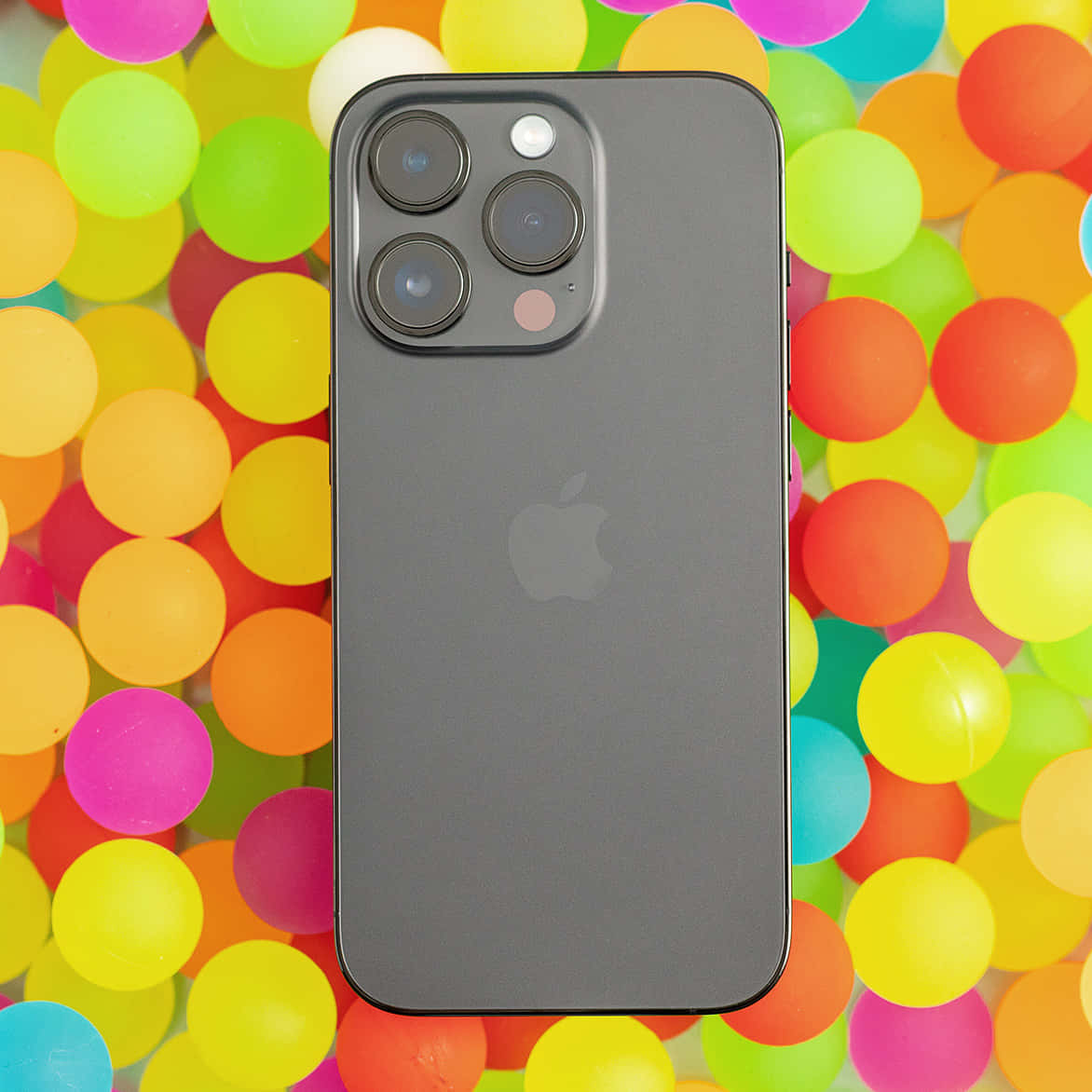 深灰色iPhone被彩色塑膠球環繞。