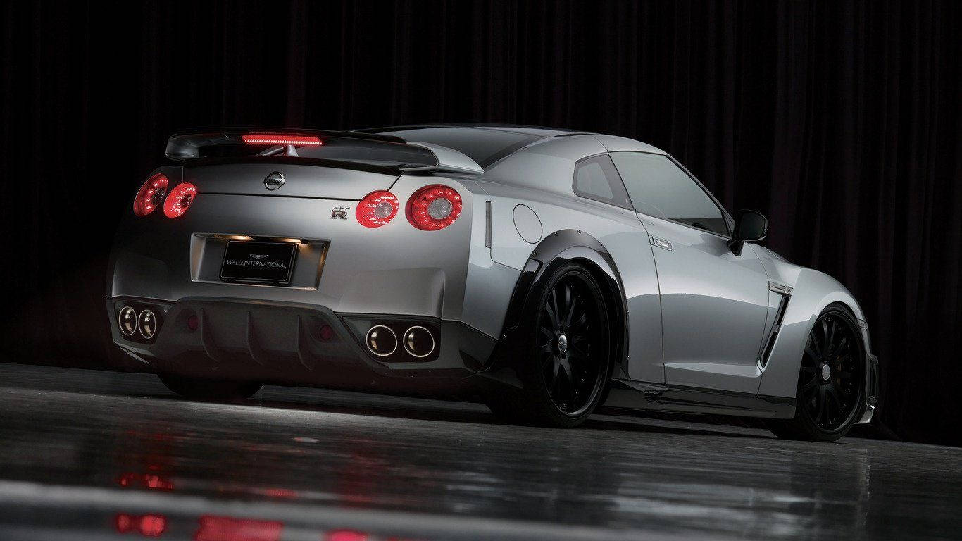 銀色日產GT-R跑車，帶紅色尾燈，在反光舞台上。