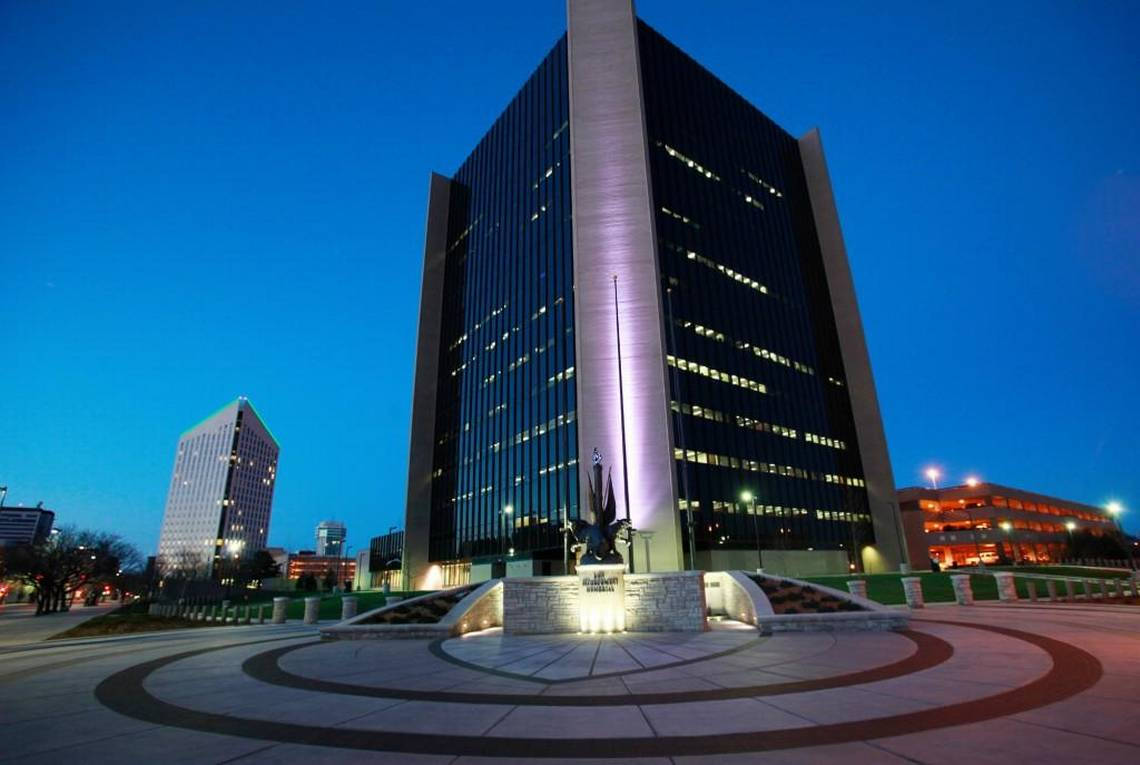 威奇托市政廳夜間燈光 壁紙 — 一座高聳的現代摩天大樓在黃昏時分亮起，發光的窗戶映襯著深藍色的天空。