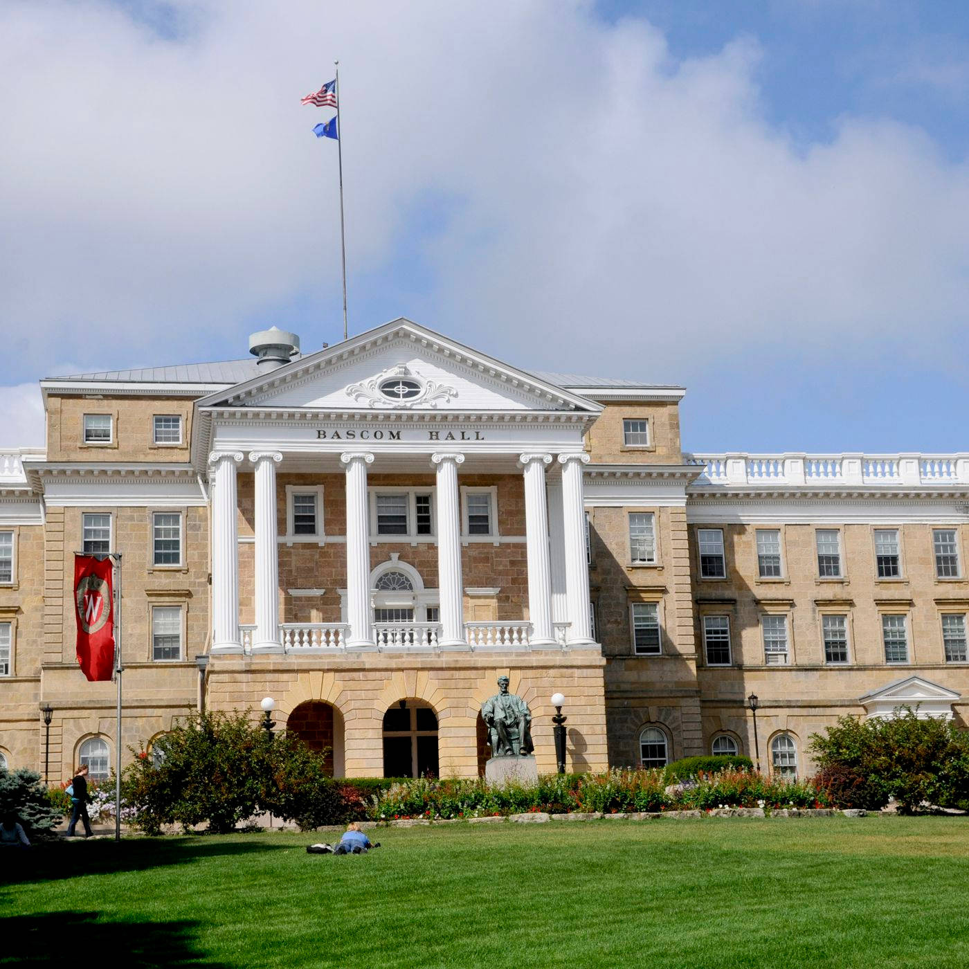 多雲天空下，帶有白色柱子和旗幟的Bascom Hall大學建築。