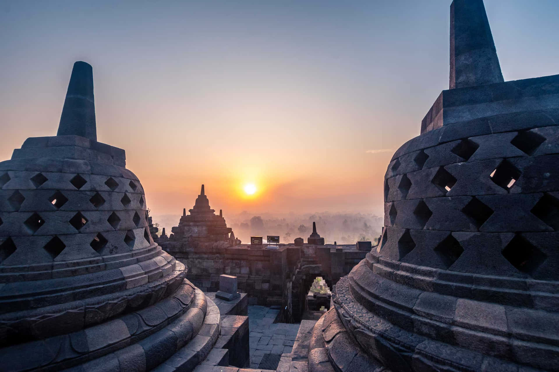 婆羅浮屠寺廟的古老石佛塔在日出時分，下方是霧氣瀰漫的山谷。