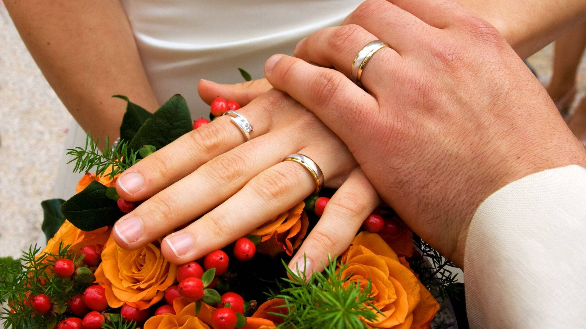 情侶的手戴著結婚戒指放在花束上。