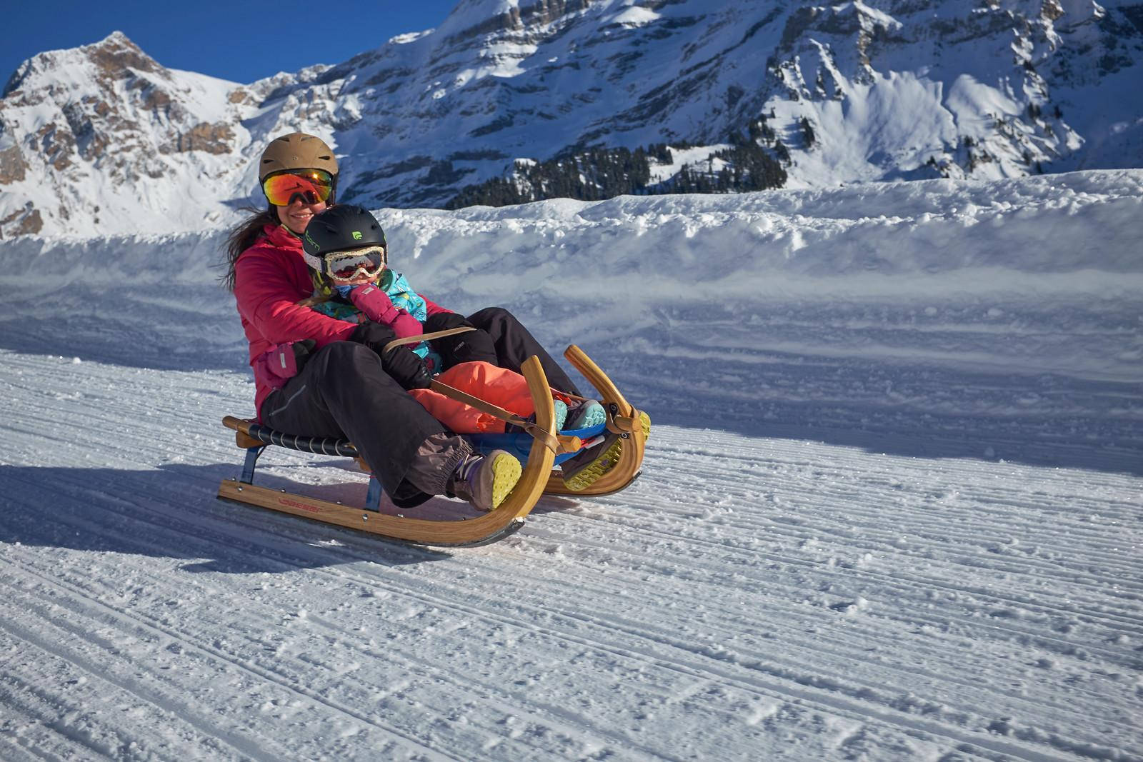 女子和小孩在雪坡上滑雪橇