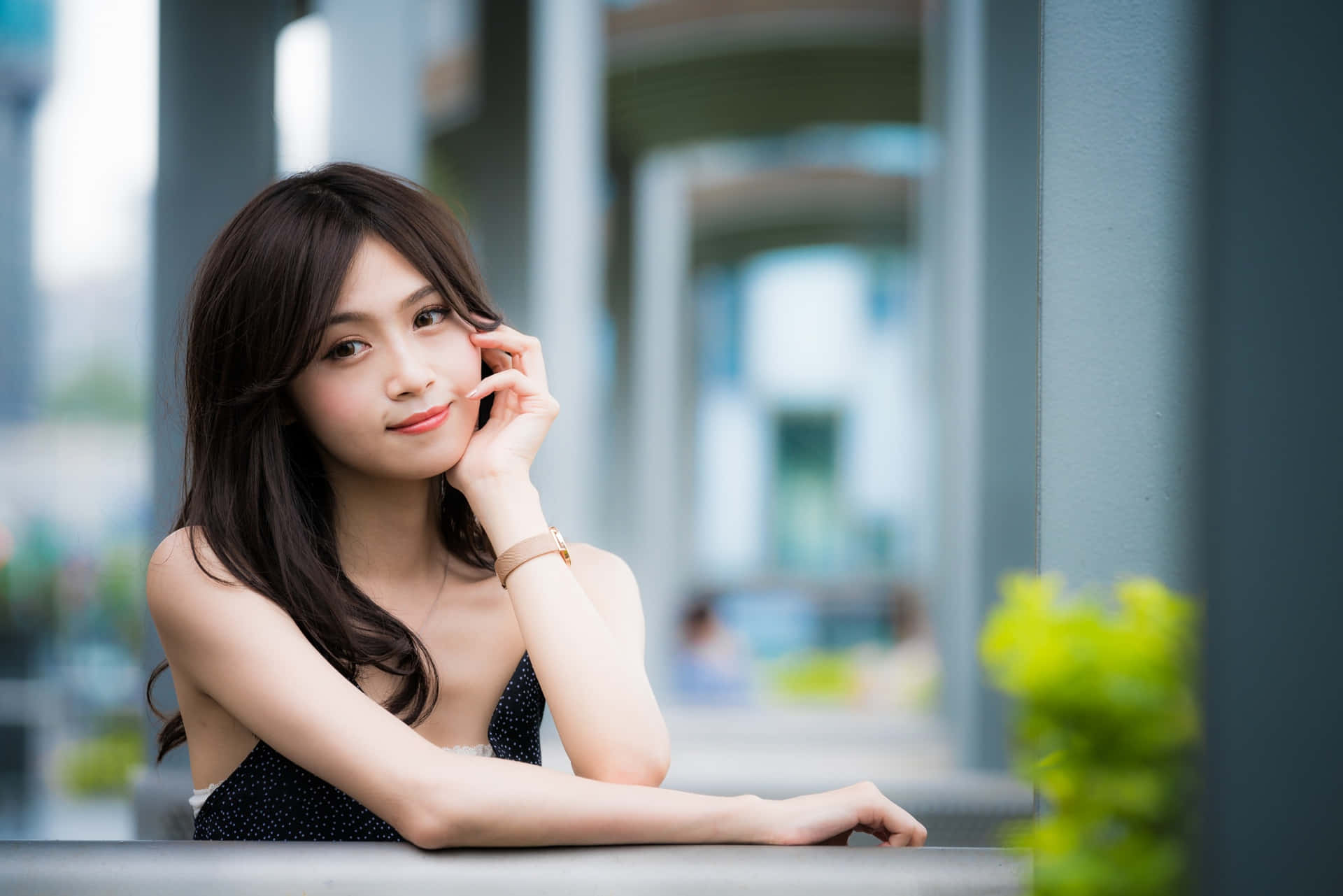 年輕女子微笑著靠在都市環境的欄杆上。
