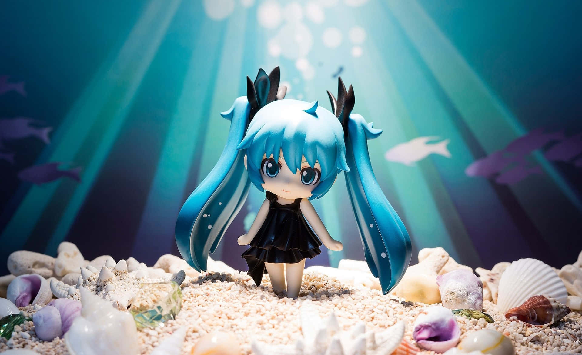 嬌小初音未來 壁紙 — 一個藍色頭髮的動漫人偶站在沙質海底，周圍環繞著貝殼，上方有陽光穿透水面。