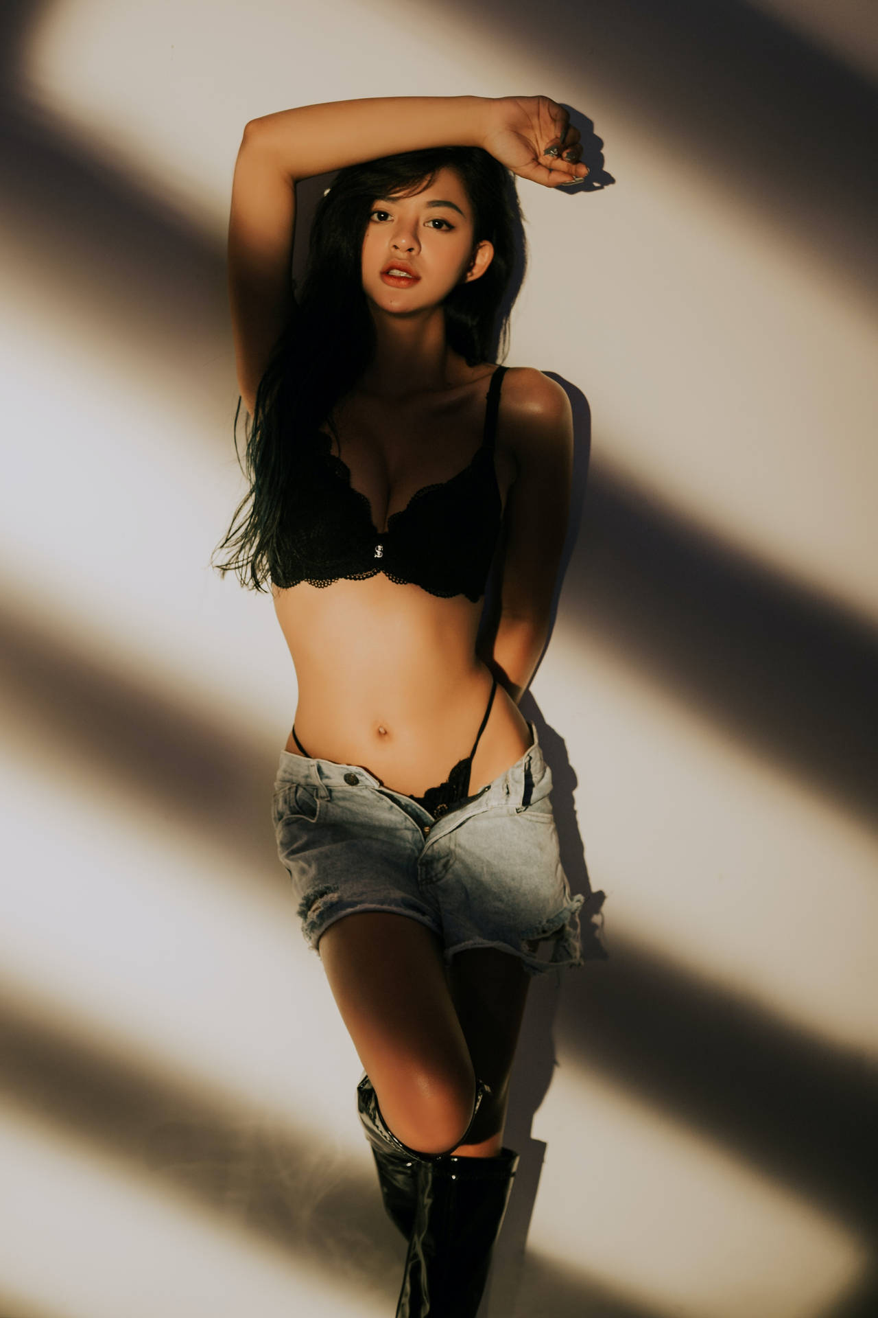 穿著黑色內衣和牛仔短褲的女性，在戲劇性燈光下擺姿勢。