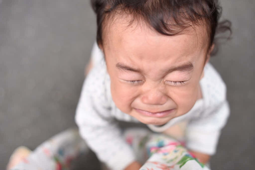 一個閉著眼睛、嘴角下垂哭泣的嬰兒。