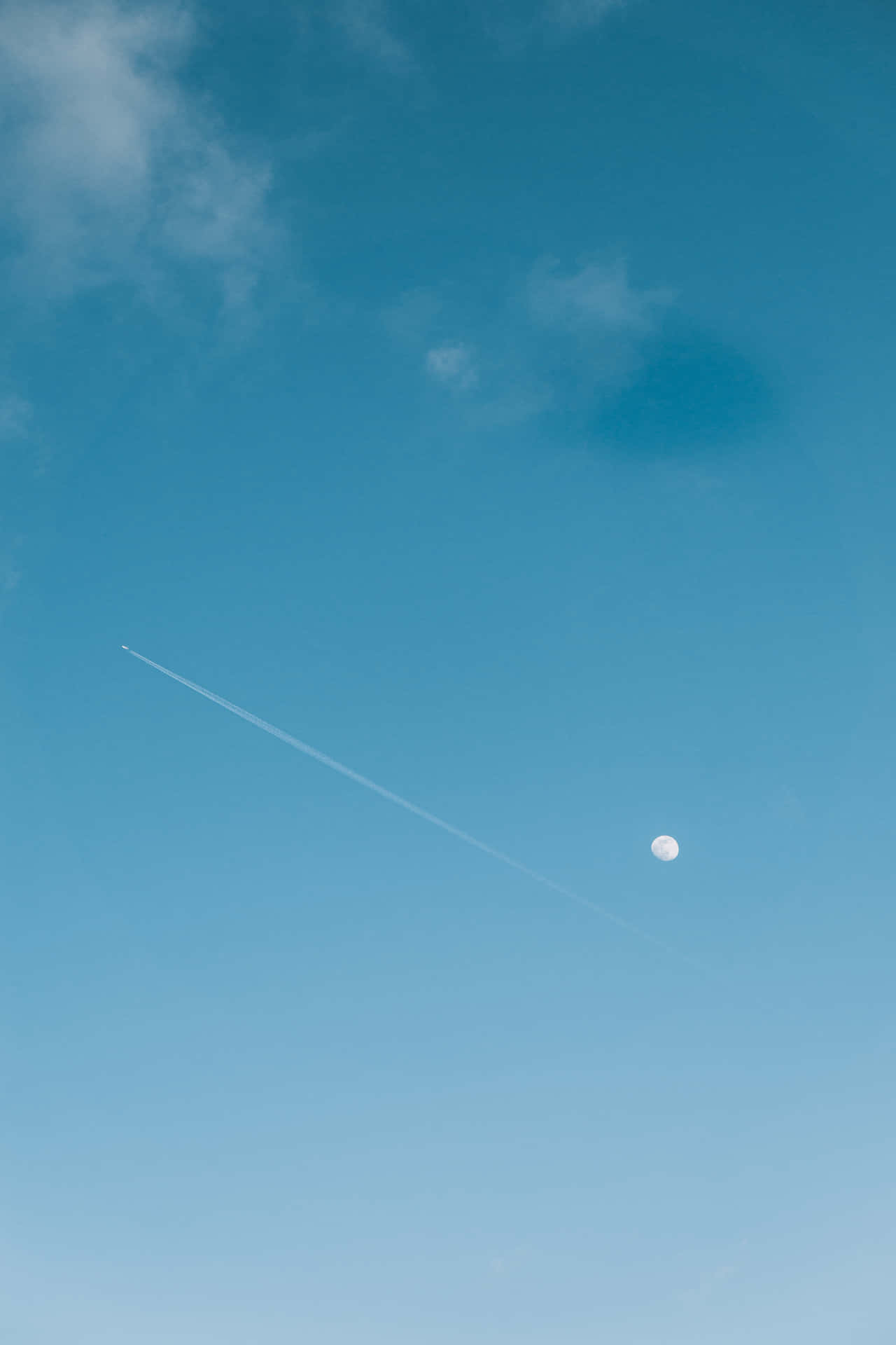 清澈藍天中的月亮和飛機雲，伴隨柔軟雲朵