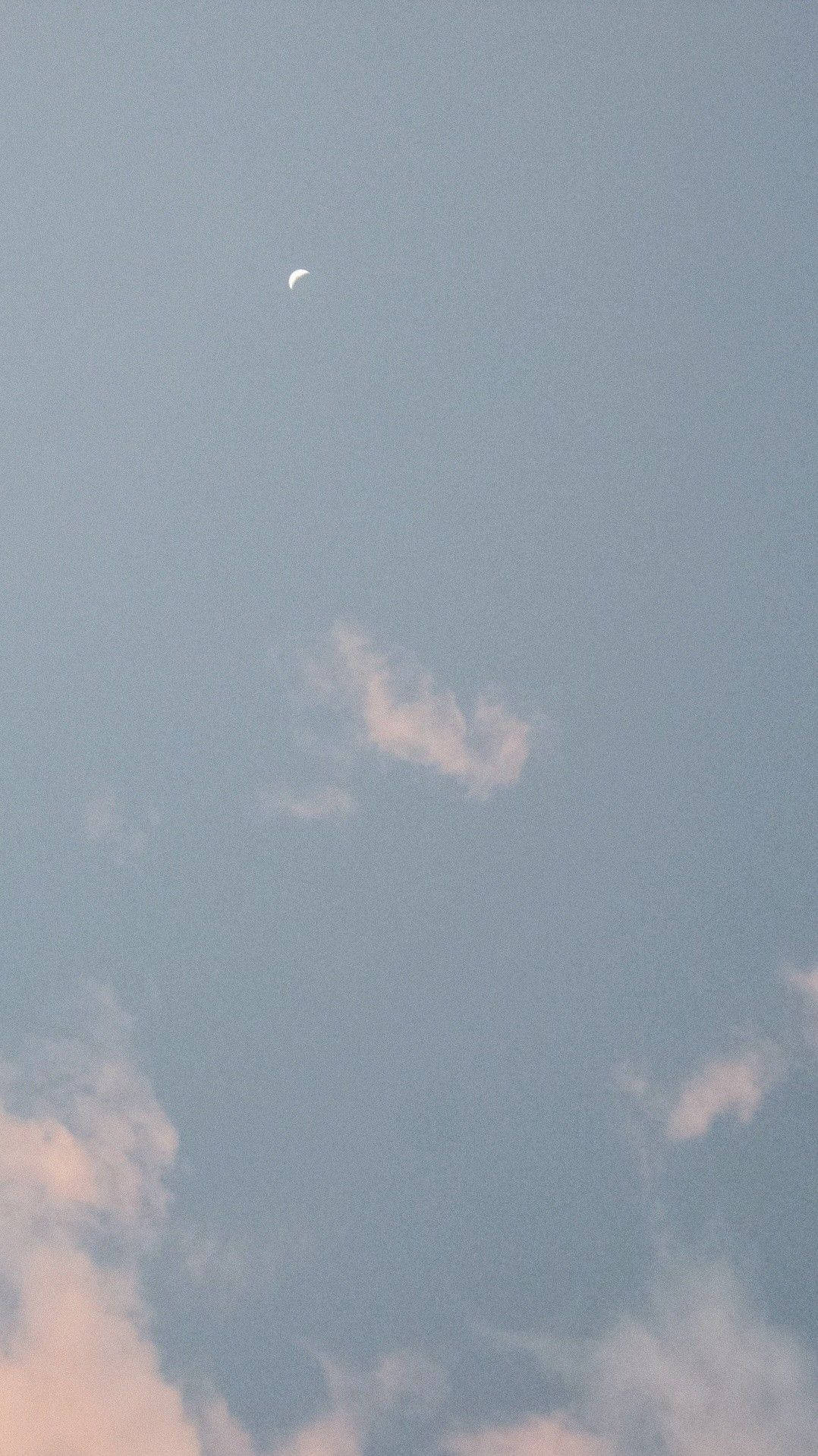 粉彩暮色天空中的月牙與散落的雲朵