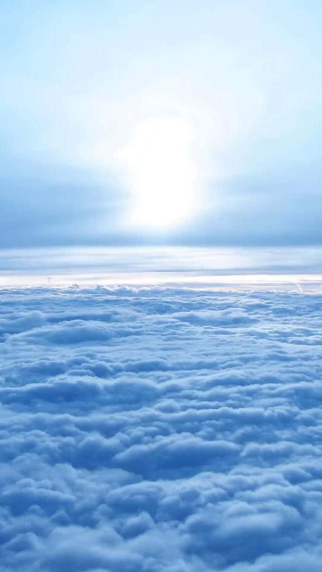 在雲層之上俯瞰一片柔軟藍色雲海，伴隨著明亮的太陽。