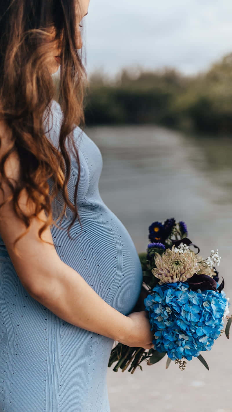 孕婦在河邊手持藍色花朵