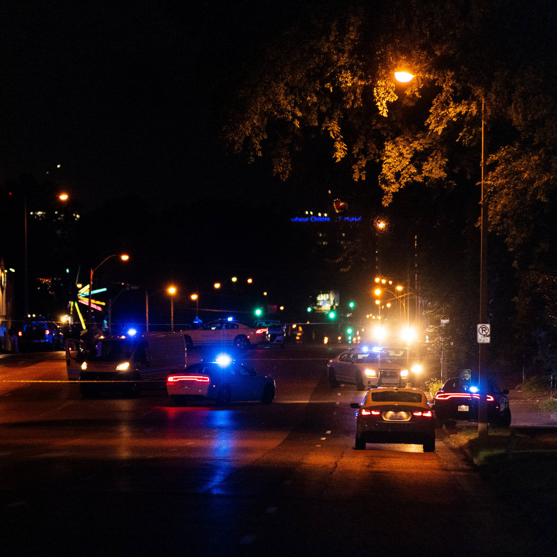 孟菲斯天際線日落 壁紙 — 夜晚街景，警車在街燈和樹下閃爍藍燈。